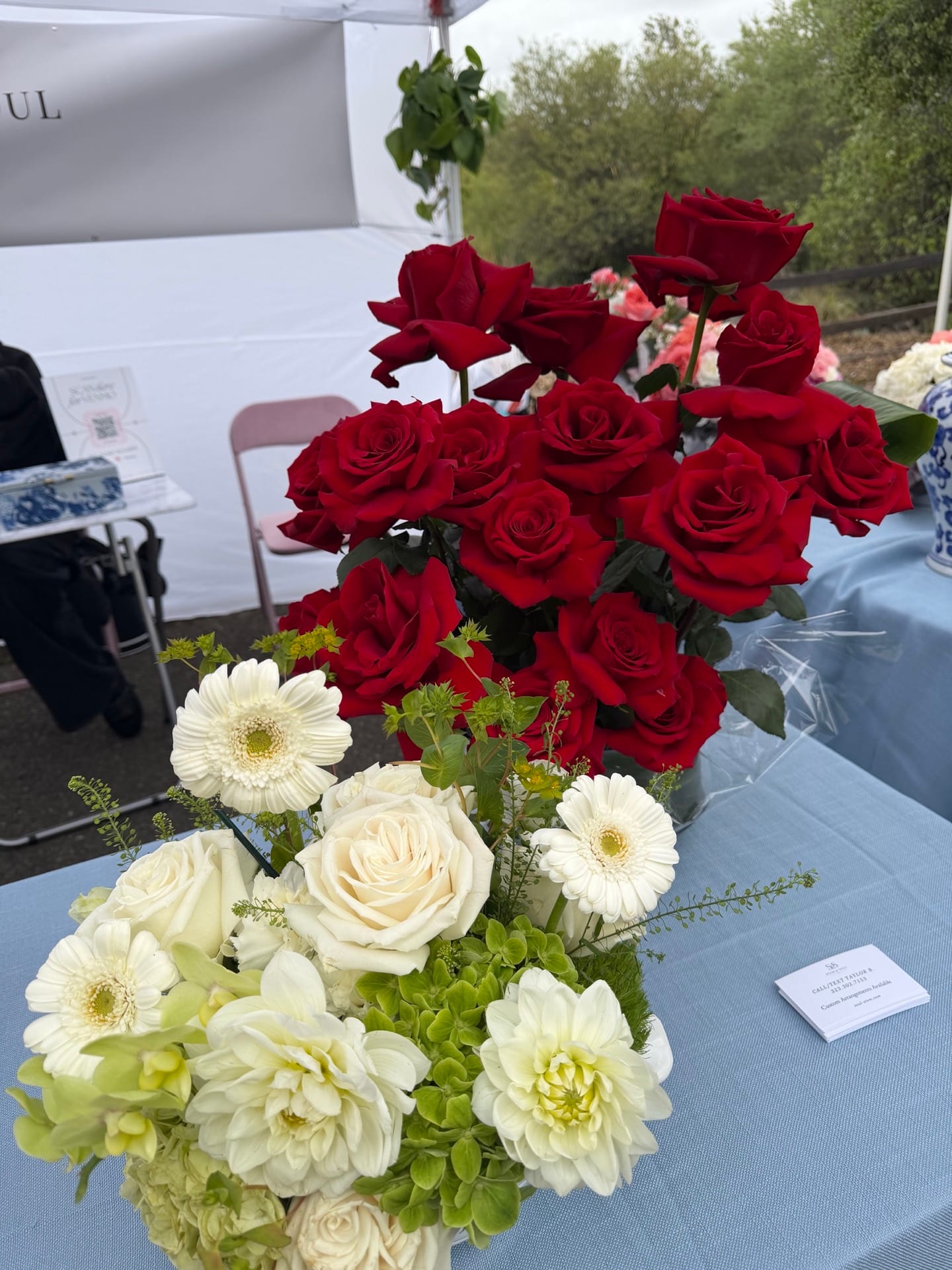 The studio at work on-site — red roses and white compositions on a setup table